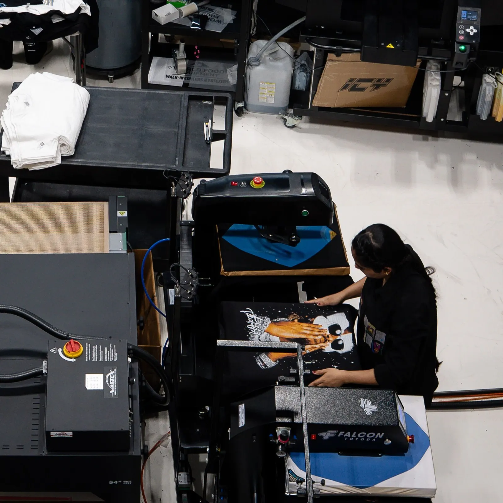An ICY printer loading a printed black tee onto the heat press on our print floor